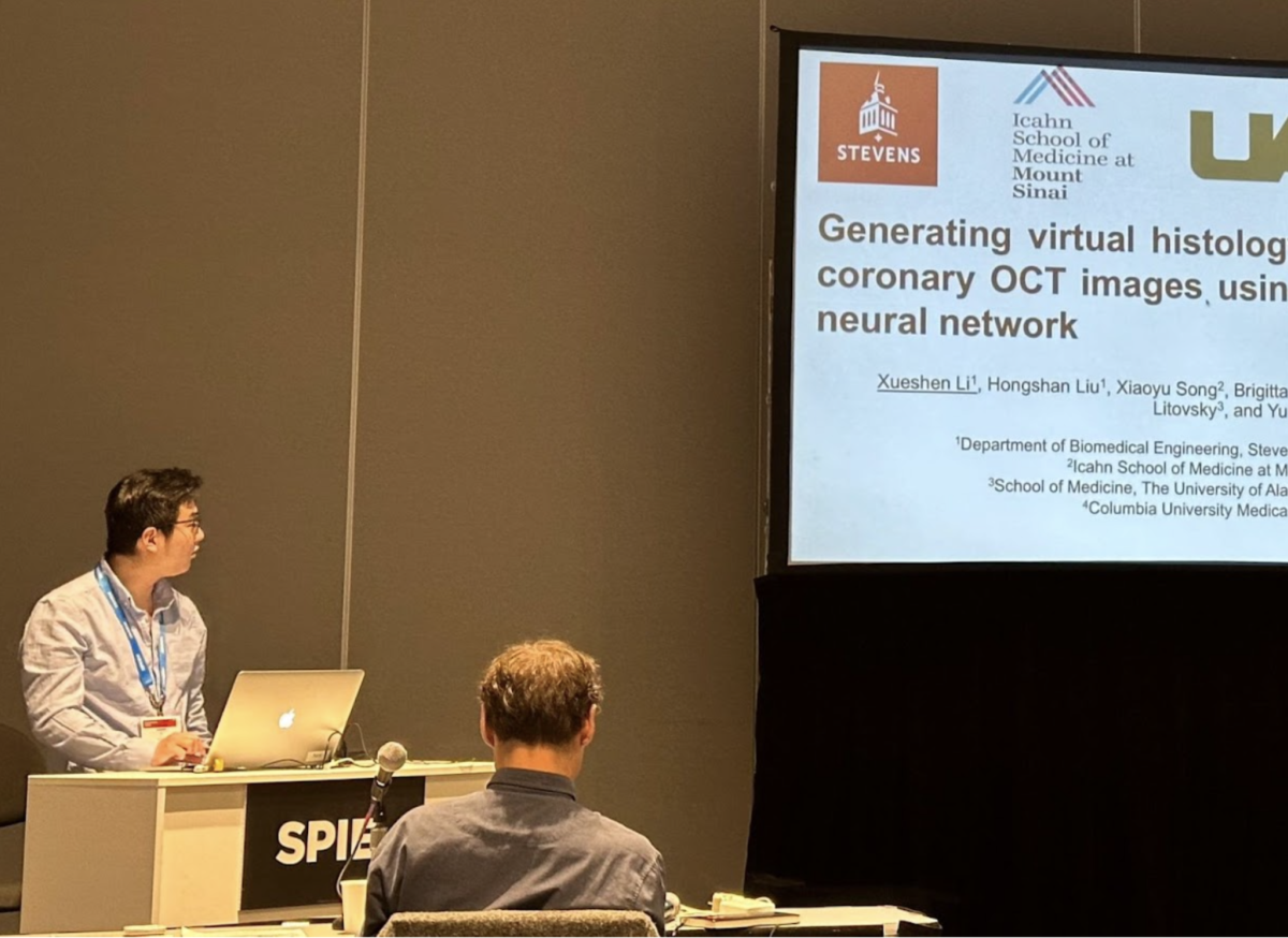 Xueshen Li stands at a podium in front of a large screen giving a presentation on his research