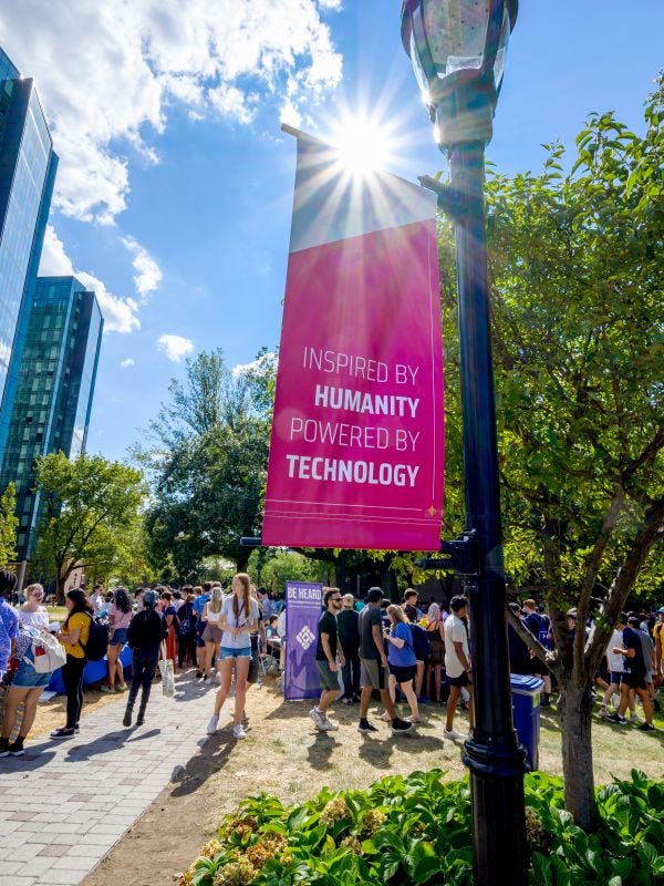 Event on Stevens campus with banner in foreground that reads "Inspired by Humanity, Powered by Technology"