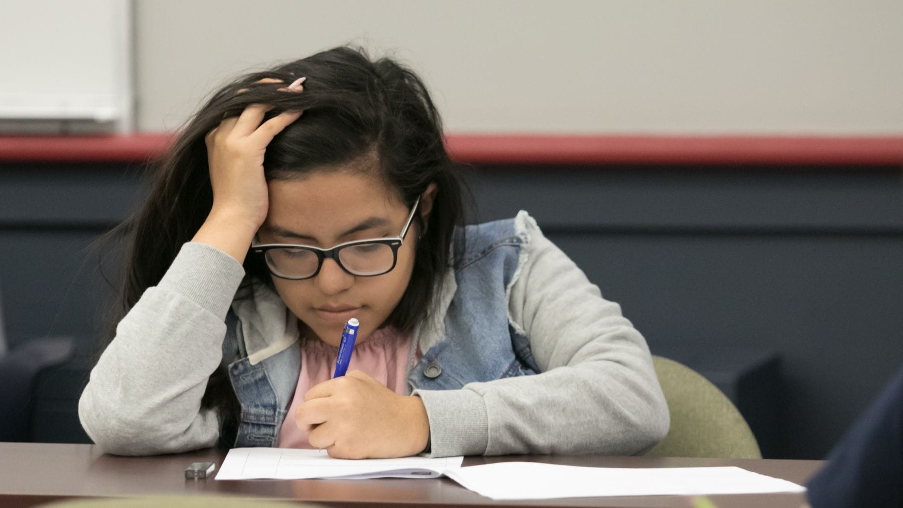 A young student concentrates as she works on a math problem