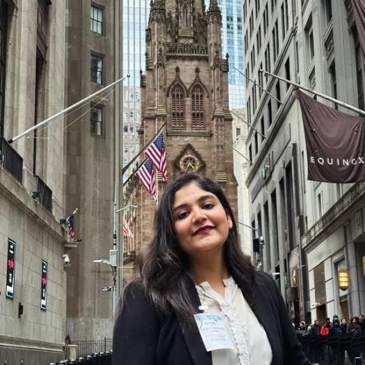 Kaushal Makadia stands on the street in New York City with the spire of a building in the background.