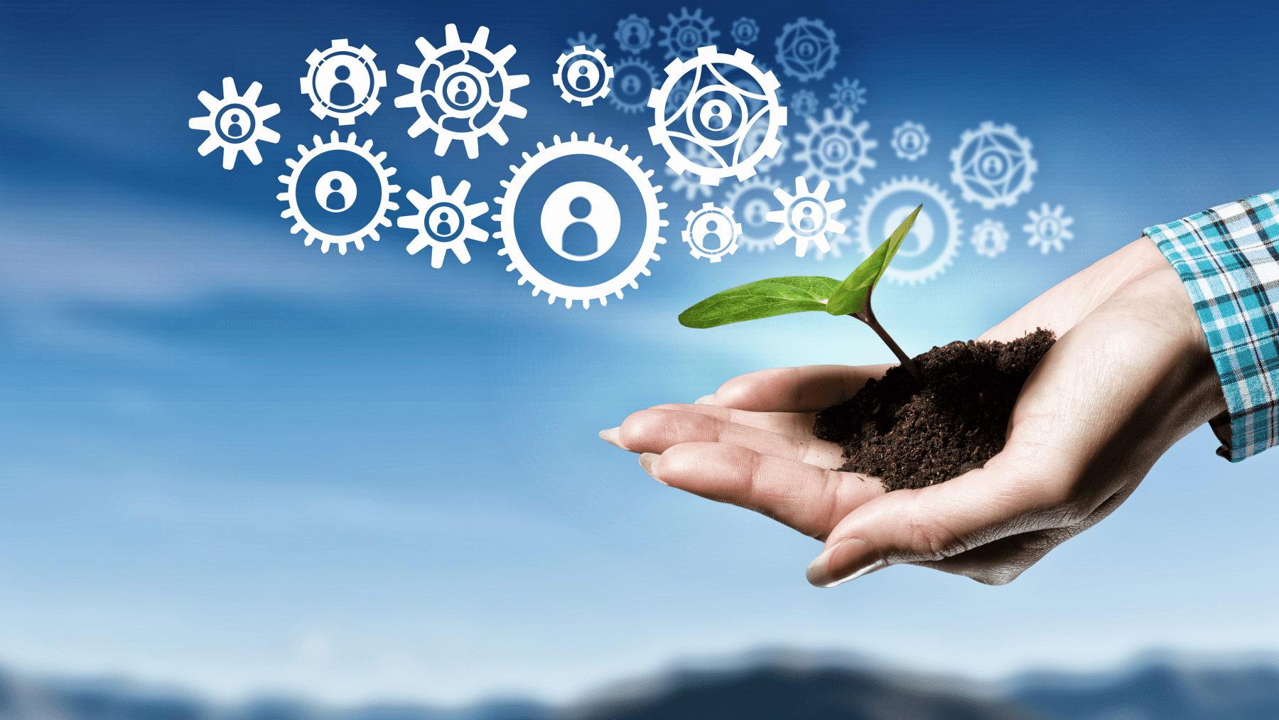 A hand holds a plant growing from soil, and coming from it are icons of gears. In the background is the sky.