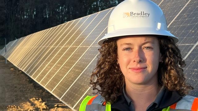 Jessica Driscoll stands in front of solar panels