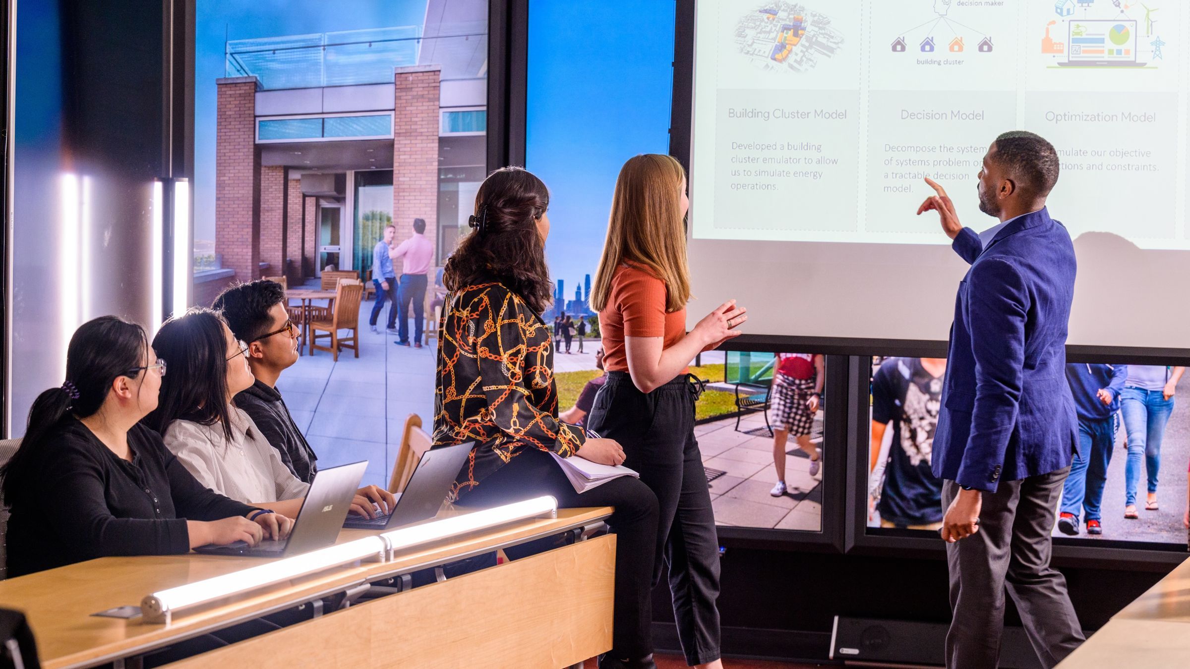 Students in a meeting room looking at a projector screen.