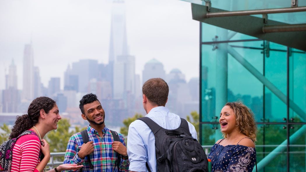 4 students laughing outside of Babbio Building