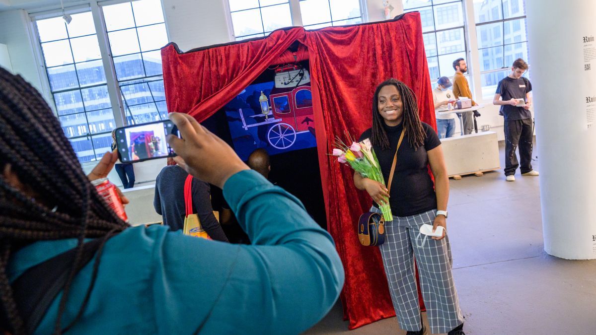 Student stands in front of her animation project at the visual arts and technology capstone exhibition.