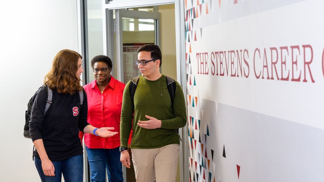 Counselor and two students walking next to Career Service sign