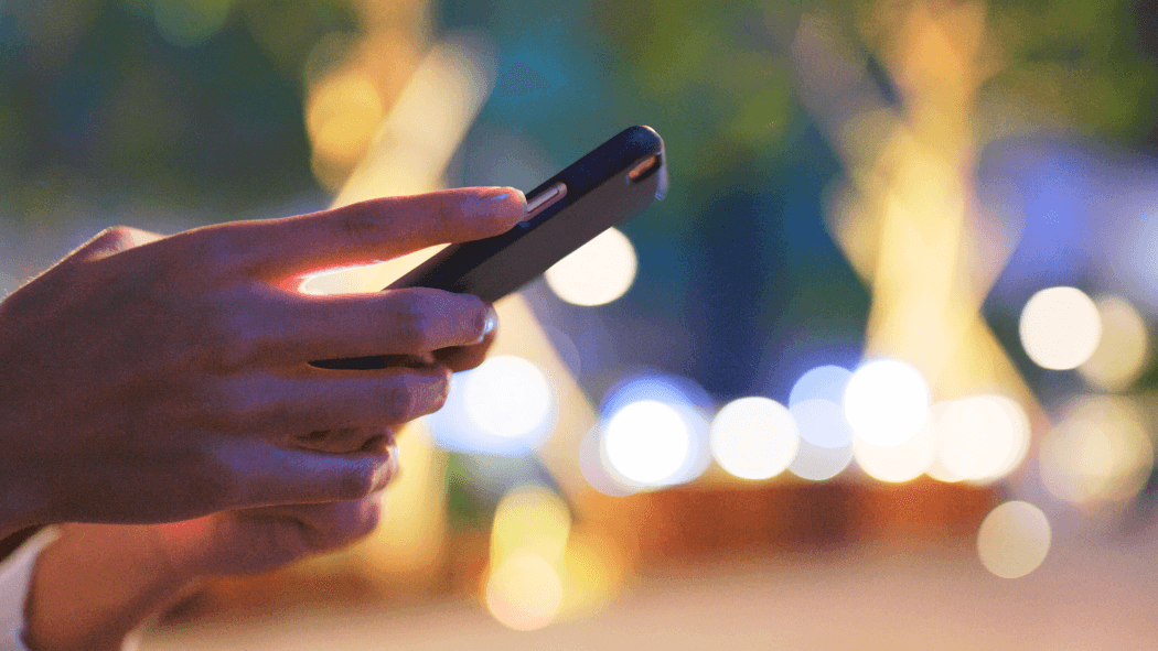 A person's hands holding a RF-sensing wireless device in a city scape.