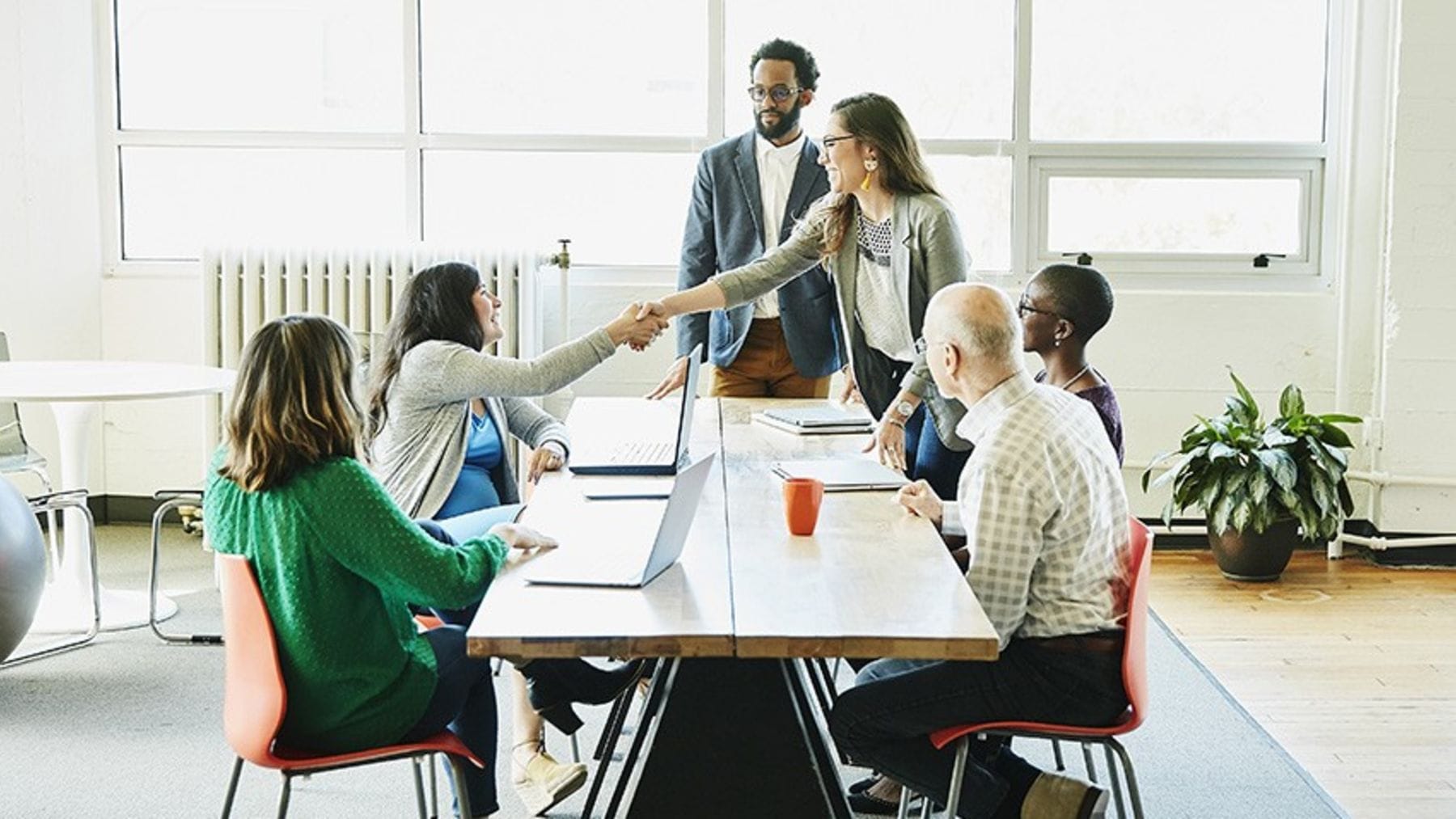 A group of young professionals meeting in a modern, open-space office at a tech startup.