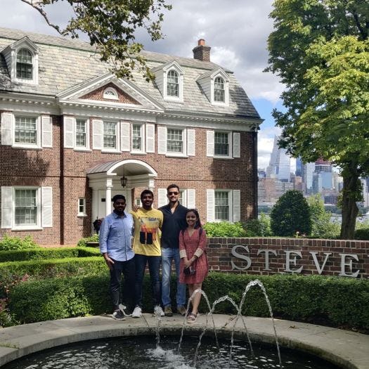 Rhythm Goyal stands with her family in front of the fountain on the Stevens campus with the New York City skyline visible in the background.