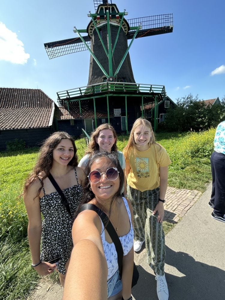 Four Stevens field hockey players pose for a selfie in front of a windmill during their summer 2023 trip