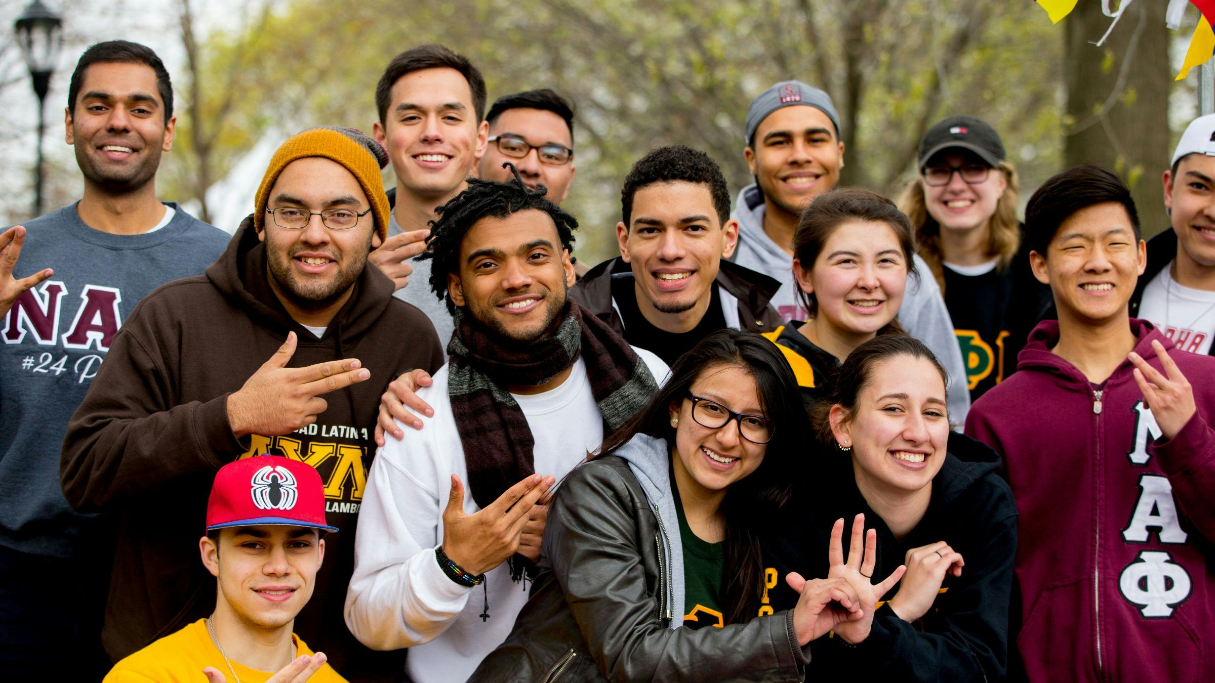 Diverse group of students smile to the camera in the fall.