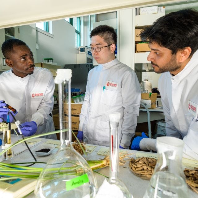 three graduate students testing materials in lab
