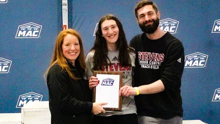 Laura Mathews receives a MAC track and field award with her coaches.