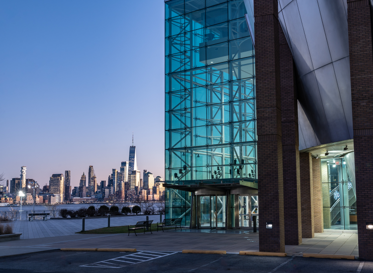 The Babbio Center with part of the New York City skyline in the background at dusk